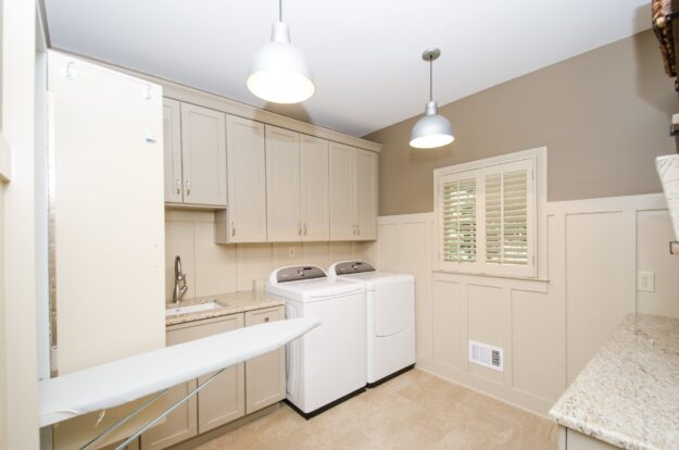 custom designed Roswell laundry room with ceiling-height cabinets separate sink and fold down laundry board