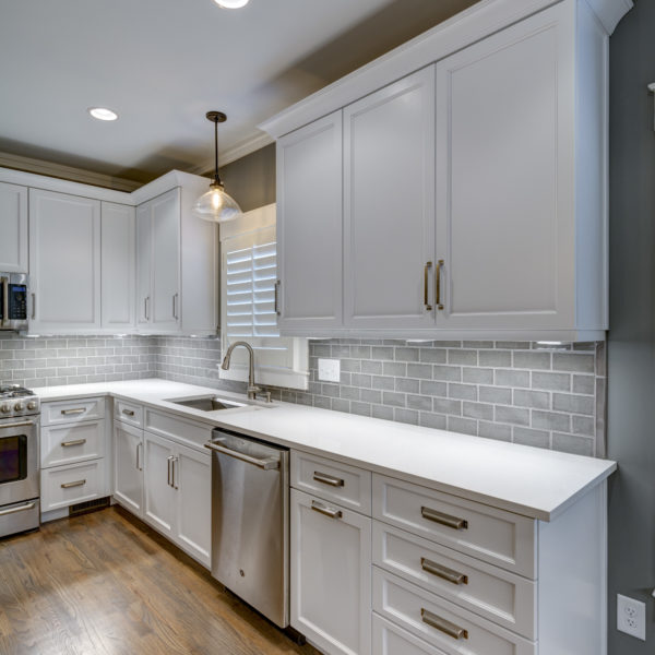 transitional kitchen design with white custom cabinets light grey subway tile large grey island luxury appliances and plantation shutters