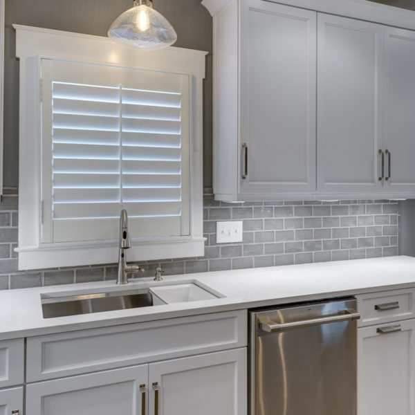 transitional kitchen design with white custom cabinets light grey subway tile large grey island luxury appliances and plantation shutters