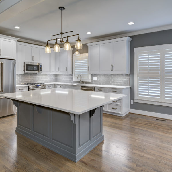 transitional kitchen design with white custom cabinets light grey subway tile large grey island luxury appliances and plantation shutters