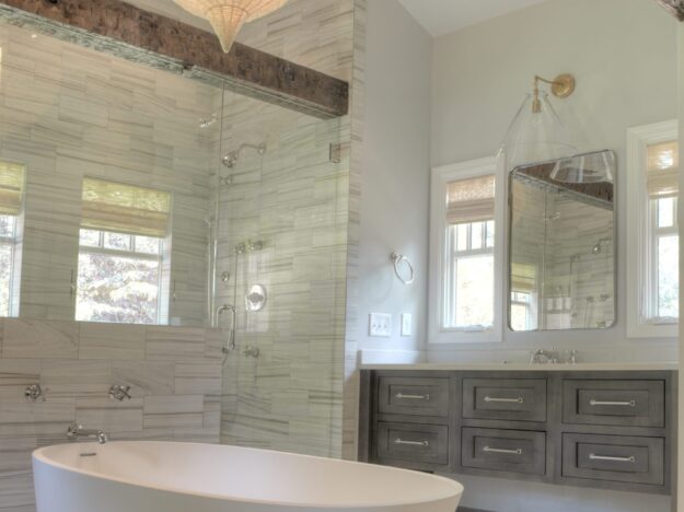 transitional bathroom renovation with large walk-in shower for two and large soaking tub with grey vanity and exposed beams