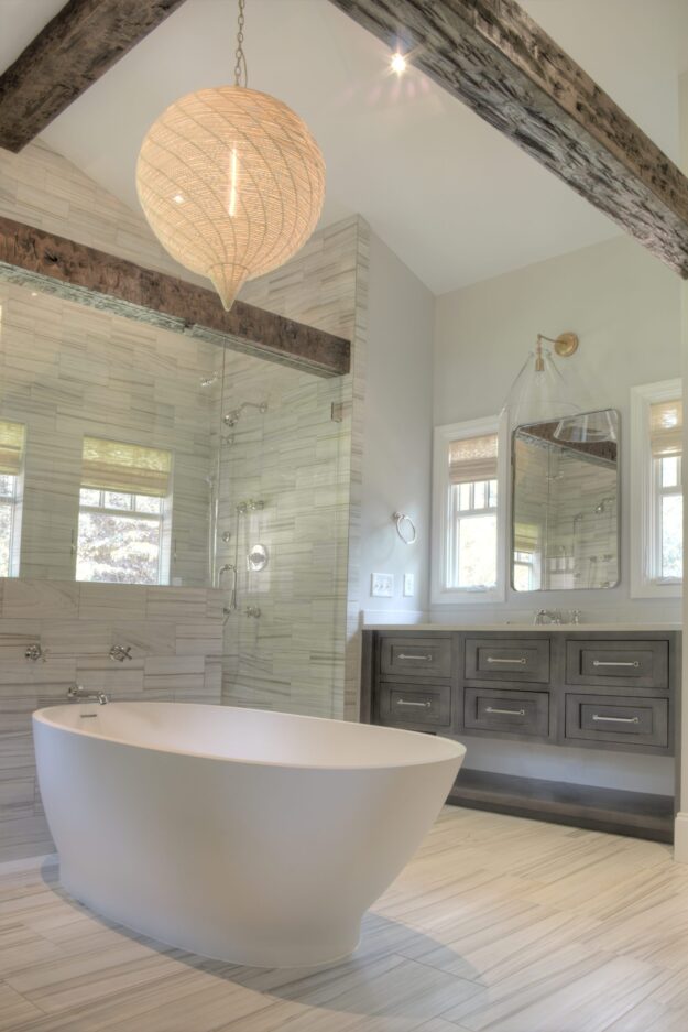 transitional bathroom renovation with large walk-in shower for two and large soaking tub with grey vanity and exposed beams