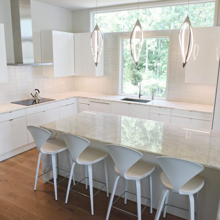 modern Atlanta white kitchen design featuring island with waterfall edge luxury appliances and contemporary pendant light fixtures