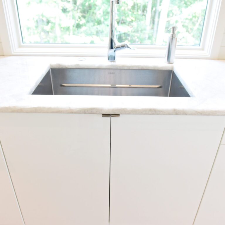 modern Atlanta white kitchen design featuring island with waterfall edge luxury appliances and contemporary pendant light fixtures