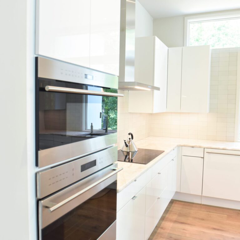 modern Atlanta white kitchen design featuring island with waterfall edge luxury appliances and contemporary pendant light fixtures