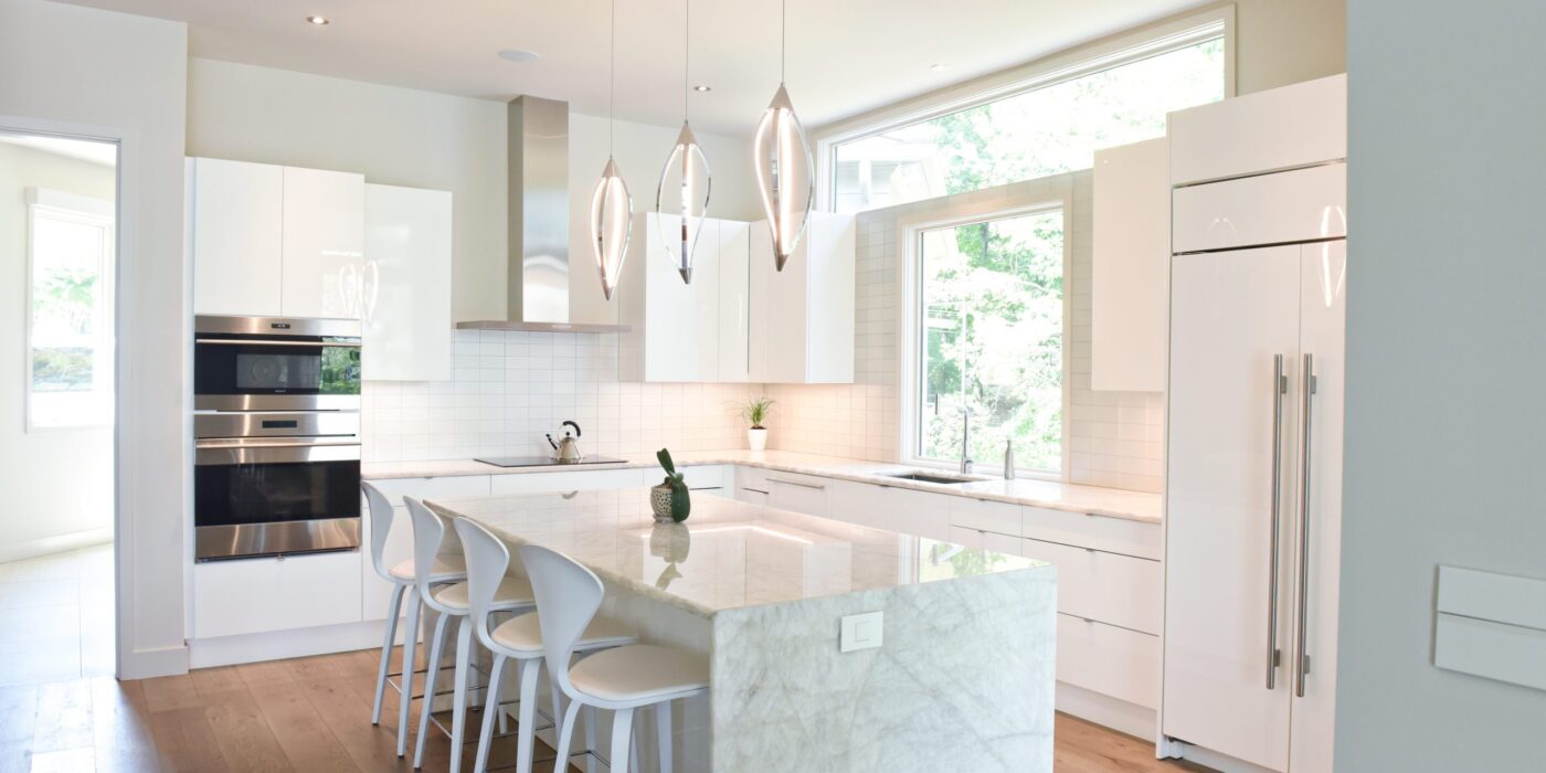 modern Atlanta white kitchen design featuring island with waterfall edge luxury appliances and contemporary pendant light fixtures