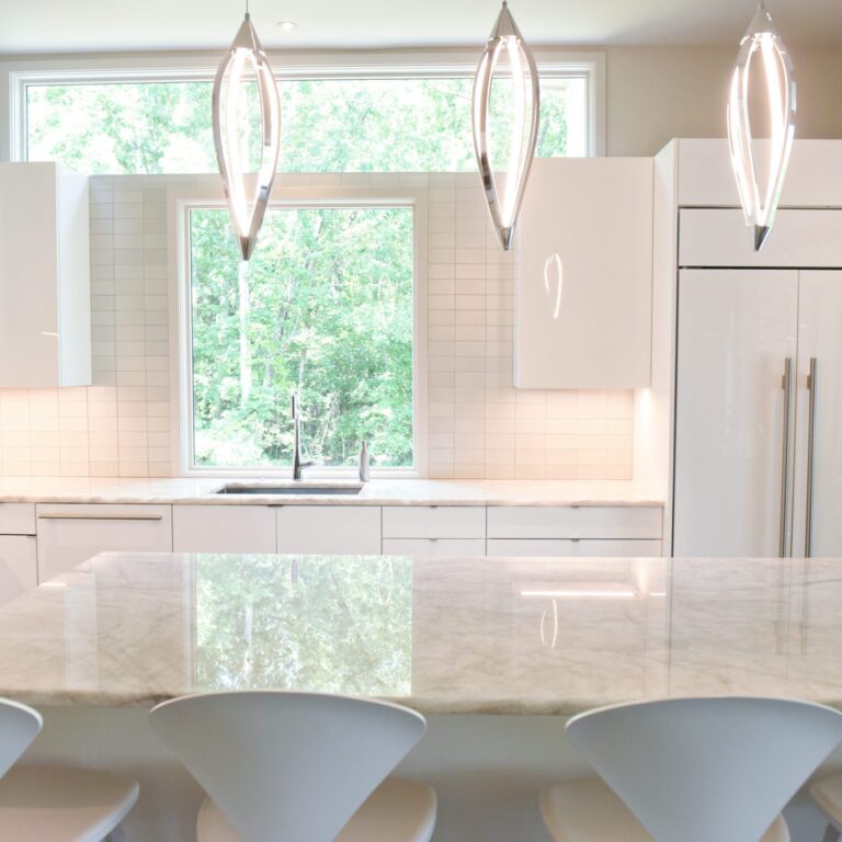 modern Atlanta white kitchen design featuring island with waterfall edge luxury appliances and contemporary pendant light fixtures