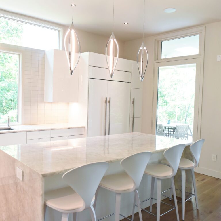modern Atlanta white kitchen design featuring island with waterfall edge luxury appliances and contemporary pendant light fixtures