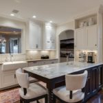 beautiful transitional kitchen with white cabinets and dark island with extra seating