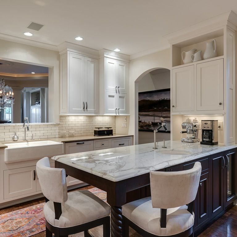 beautiful transitional kitchen with white cabinets and dark island with extra seating