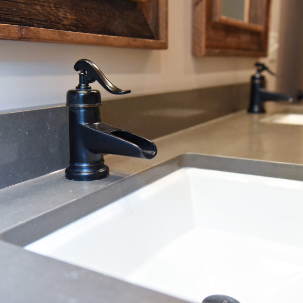 Close up image of black faucets on rustic vanity in modern mountain cabin