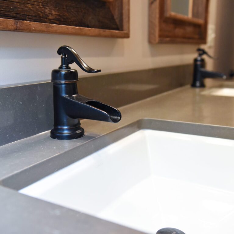 Close up image of black faucets on rustic vanity in modern mountain cabin