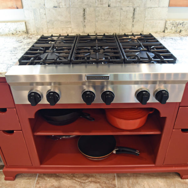 rustic kitchen renovation with custom grey cabinets large island with seating for four red pops of color on accent cabinets floating shelves exposed beams