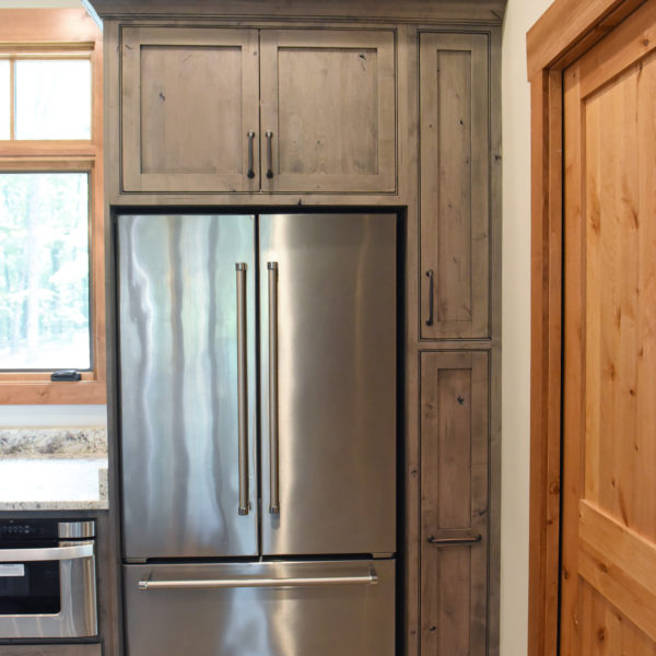 rustic kitchen renovation with custom grey cabinets large island with seating for four red pops of color on accent cabinets floating shelves exposed beams