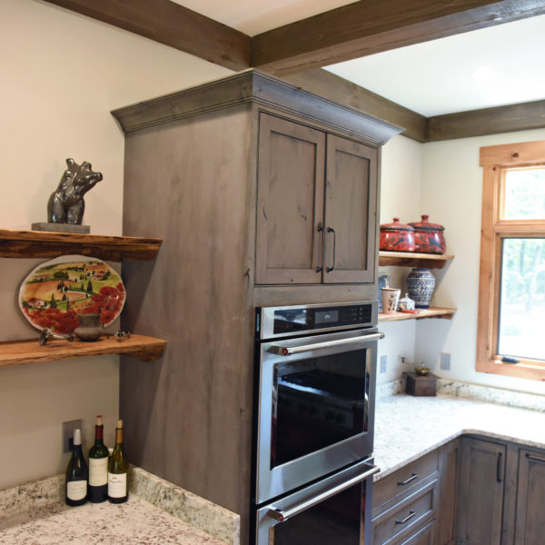 rustic kitchen renovation with custom grey cabinets large island with seating for four red pops of color on accent cabinets floating shelves exposed beams