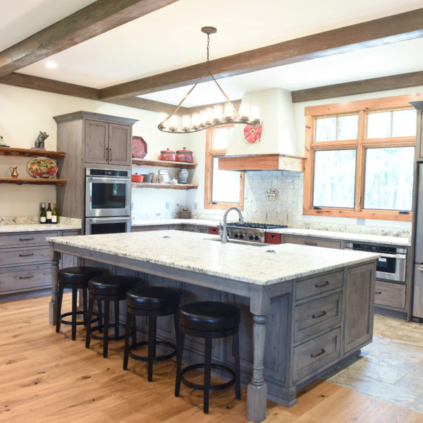 rustic kitchen renovation with custom grey cabinets large island with seating for four red pops of color on accent cabinets floating shelves exposed beams