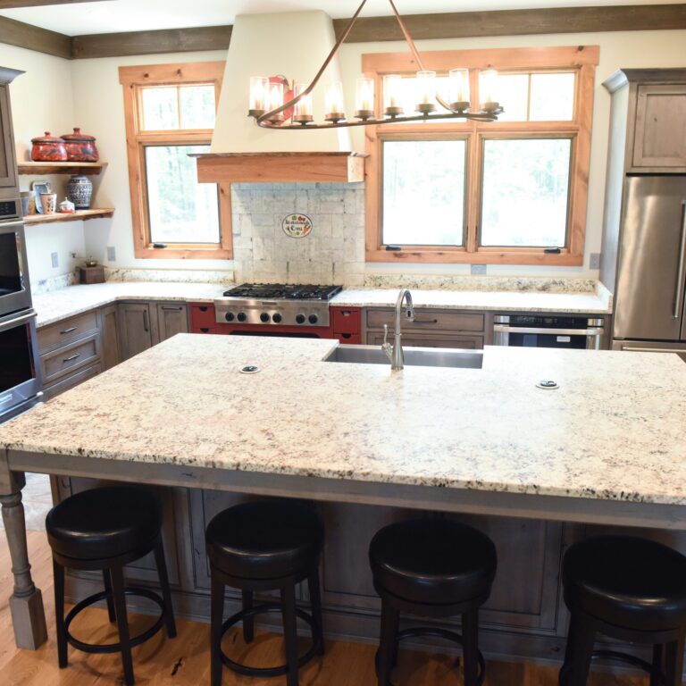 rustic kitchen renovation with custom grey cabinets large island with seating for four red pops of color on accent cabinets floating shelves exposed beams