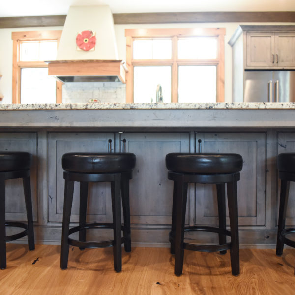 rustic kitchen renovation with custom grey cabinets large island with seating for four red pops of color on accent cabinets floating shelves exposed beams