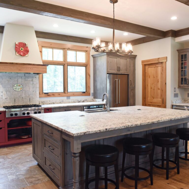 rustic kitchen renovation with custom grey cabinets large island with seating for four red pops of color on accent cabinets floating shelves exposed beams