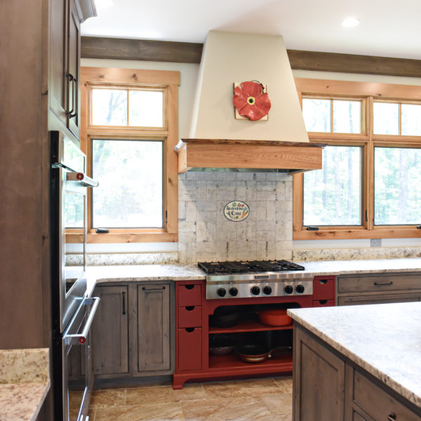 rustic kitchen renovation with custom grey cabinets large island with seating for four red pops of color on accent cabinets floating shelves exposed beams