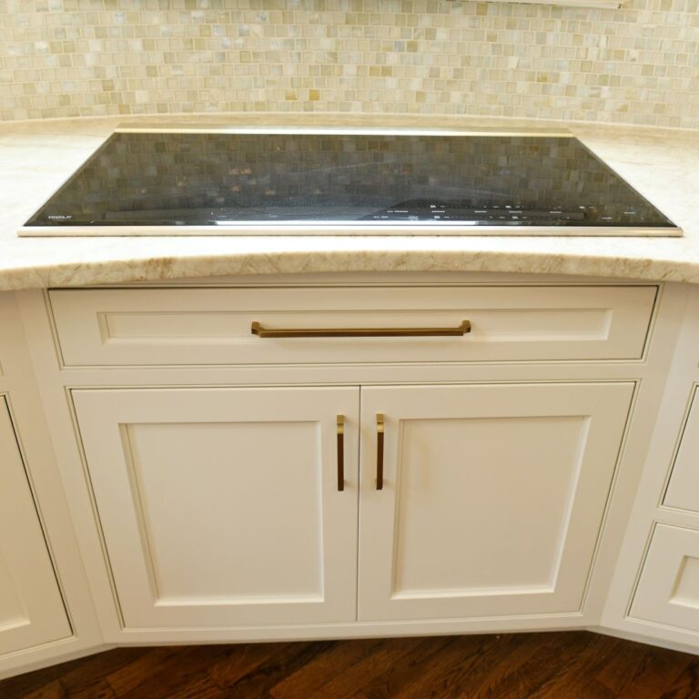 closed up of cooktop with vent hidden in award-winning Atlanta kitchen features white custom curved base cabinets with elegant curved contrasting dark island