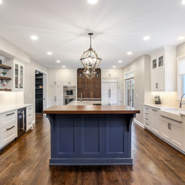 beautiful kitchen renovation in Roswell GA featuring large blue island with white upper and lower kitchen cabinets luxury appliances high-end light fixtures