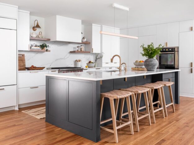 close up of dark blue kitchen island with seating for four in contemporary Atlanta kitchen renovation that features sleek white cabinets with gold hardware and lots of custom storage space