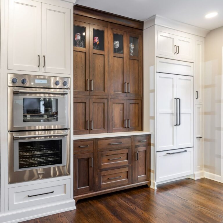 a brown accent cabinet is flanked by a double oven and concealed refrigerator in this gorgeous Roswell GA kitchen renovation project