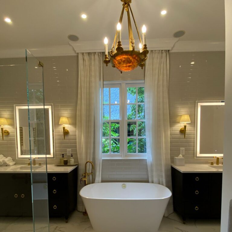 beautiful bathroom renovation featuring double vanities, a soaking tub, and amazing chandelier