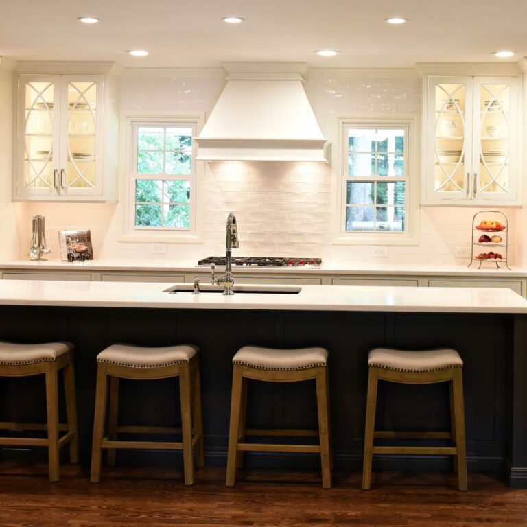 this picture-perfect Atlanta kitchen makeover has a large island, small white vent hood, white custom cabinets with glass doors and custom inserts