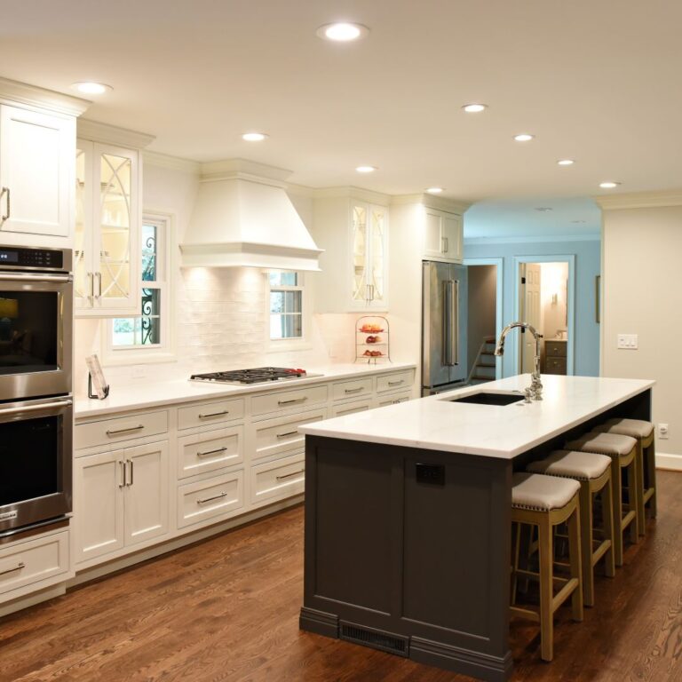 This transitional kitchen renovation includes a large grey island luxury appliances white custom cabinets and recessed lighting