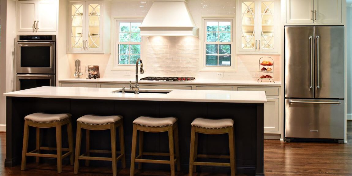 this Atlanta kitchen renovation features a large island with seating for four custom white wall and base cabinets, luxury stainless steel appliances