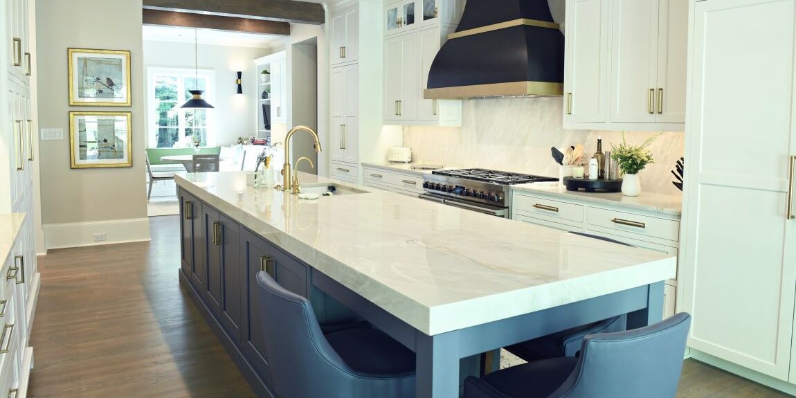 picture of a beautiful buckhead kitchen renovation with white cabinets and blue island with large black vent hood with brass trim
