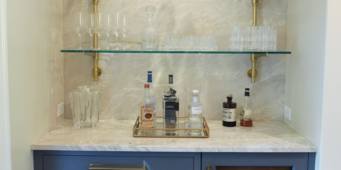view of home bar with blue cabinet and brass hardware and glass shelves in buckhead