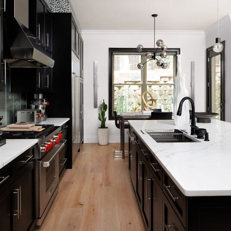 this beautiful kitchen remodel in Alpharetta features sleek black cabinets, white counters, and luxury appliances