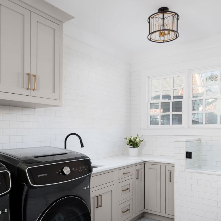 this laundry room features an elevated dog washing area, custom cabinets, white subway tile in buckhead atlanta GA