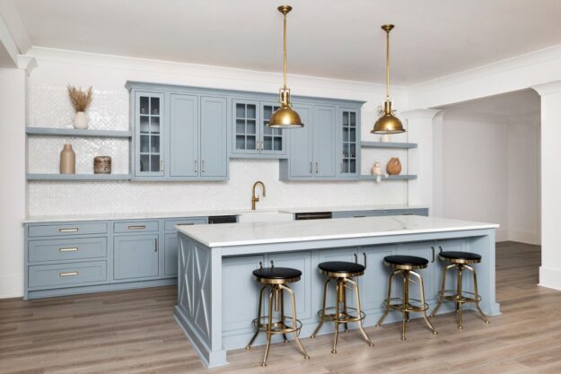 this beautiful basement kitchenette in buckhead atlanta, GA features custom light blue cabinets, an island with seating for four, and gorgeous white counters