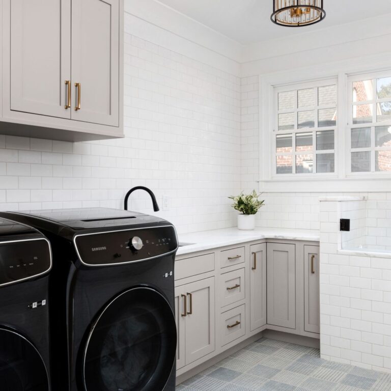 this beautiful laundry room in buckhead features light taupe cabinets, white subway tile, white counters, and a custom dog wash area