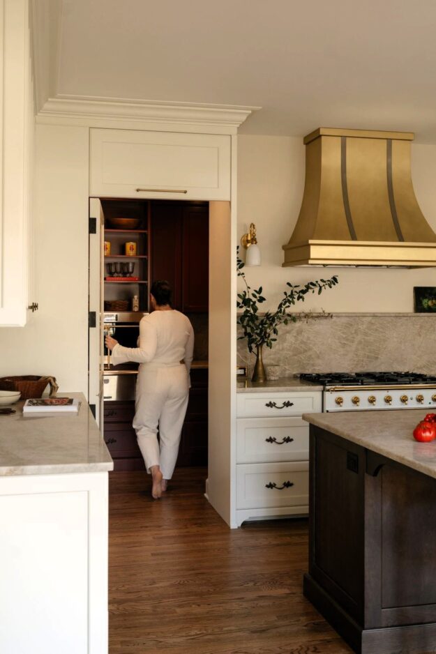 picture of homeowner stepping into hidden pantry in luxury kitchen in Sandy Springs