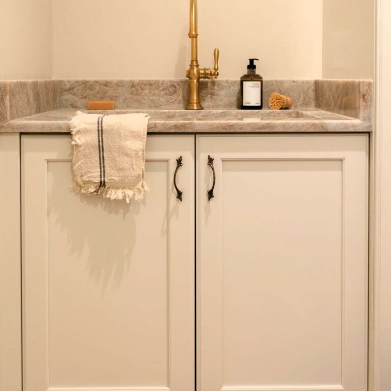 close up of a sink in a mudroom of a Sandy Springs home featuring a Mouser cabinet in Alpine color with a quartzite top and brushed gold faucet