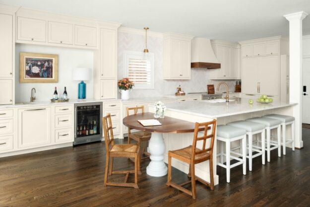 Vinings kitchen remodel featuring Mouser Cabinets in Benjamin Moore Creamy with Taj Mahal quartzite countertops with a custom half dining table integrated into kitchen island with wood top by Against the Grain WoodTops