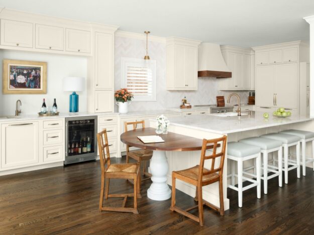 Vinings kitchen remodel featuring Mouser Cabinets in Benjamin Moore Creamy with Taj Mahal quartzite countertops with a custom half dining table integrated into kitchen island with wood top by Against the Grain WoodTops