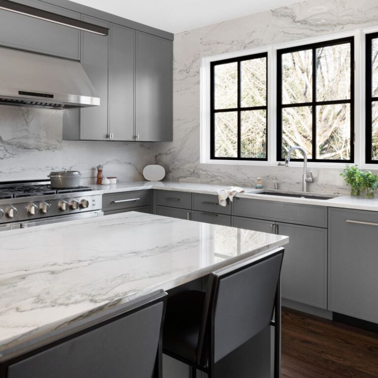 picture of island with white quartzite counter with grey veining in a Buckhead kitchen remodel showing corner of cabinets and windows with black frames