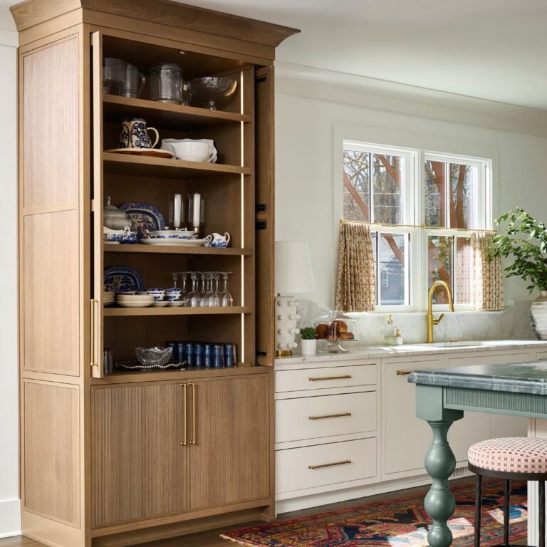 Custom Atlanta kitchen featuring a warm wood display cabinet, white cabinetry, brass fixtures, green furniture-style island, and layered traditional details with marble countertops and vintage-inspired rug