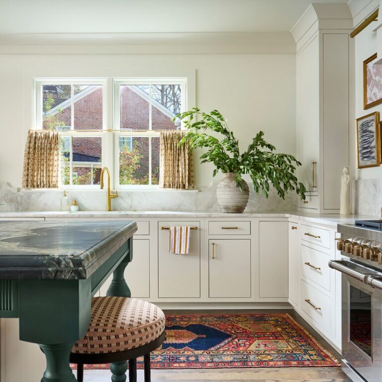 Atlanta kitchen renovation with custom white cabinetry, marble countertops, green island with turned legs, brass fixtures, Wolf range, and colorful vintage-inspired runner rug