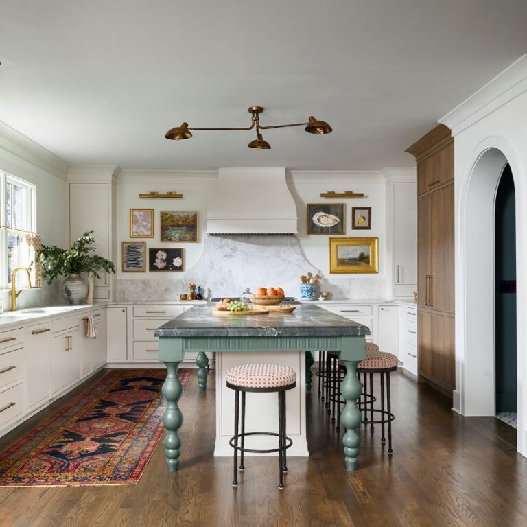 Tailored Atlanta kitchen renovation featuring custom white cabinetry, warm wood accents, a green furniture-style island with marble countertop, brass fixtures, decorative range hood, and colorful vintage runner rug