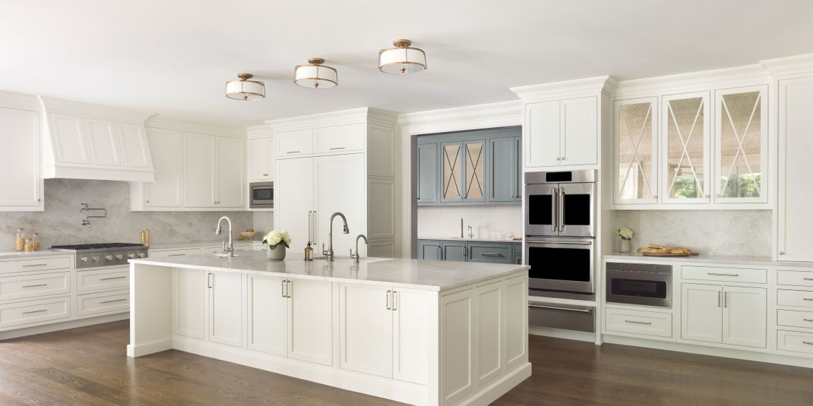 Angled view of white transitional Roswell kitchen with large island and blue-gray prep area