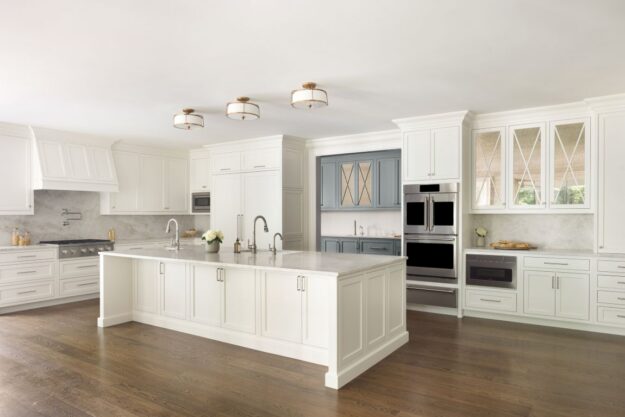Angled view of white transitional Roswell kitchen with large island and blue-gray prep area