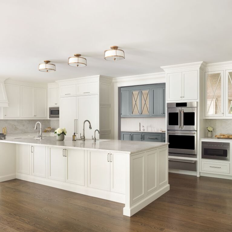 Angled view of white transitional Roswell kitchen with large island and blue-gray prep area