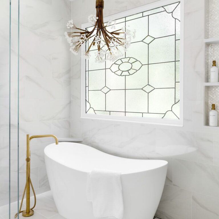 Glass-enclosed wet room with freestanding tub, porcelain tile, and brushed-gold fixtures